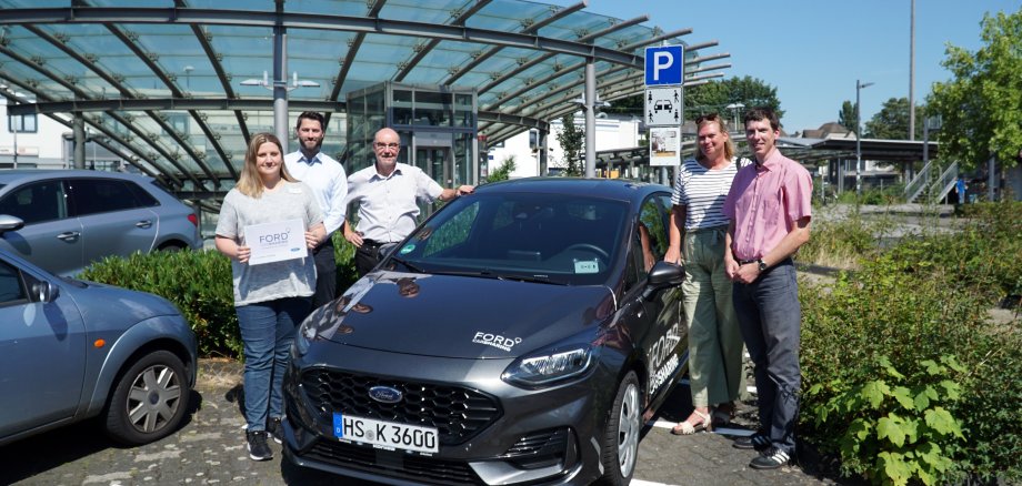 Menschen und ein Auto am Bahnhof