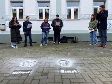 Von Links: Vier Schüler*innen der Klasse 9b der Gemeinschaftshauptschule erinnern an das Schicksal der Familie Harf. Eva Jabs, Leiterin der Kita, die sich seit 2020 im Harf-Haus befindet, und Bürgermeister Stephan Muckel lauschen ergriffen.