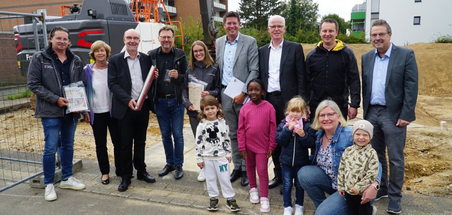 Beteiligte aus Rathaus und Politik sowie dem Architekturbüro füllten gemeinsam mit Kita-Kindern eine Zeitkapsel, die Bürgermeister Stephan Muckel zusammen mit dem Grundstein in der Erde vergrub.